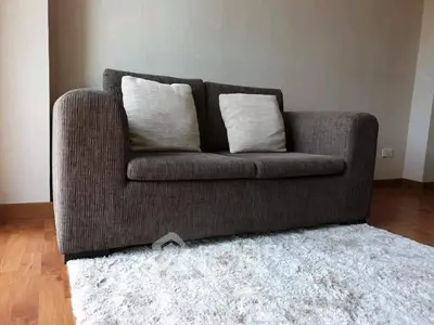 Cozy living room with plush sofa and soft rug on wooden floor.