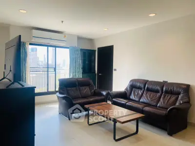 Spacious living room with leather sofas and city view window in modern apartment.