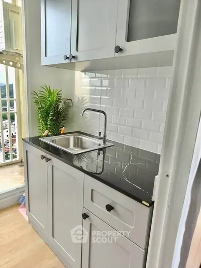 Chic modern kitchen with sleek black countertop and stylish cabinetry, perfect for urban living.