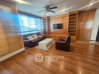 Spacious living room with wooden flooring, built-in shelves, and modern furniture.