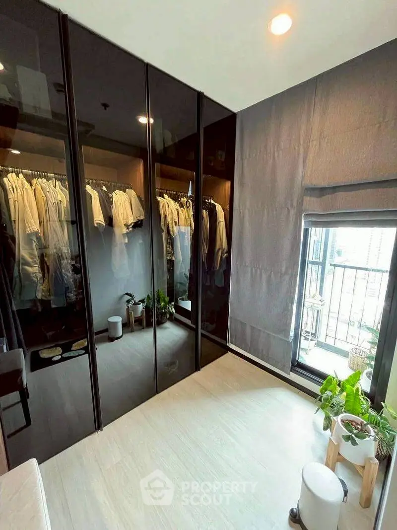 Modern bedroom with sleek glass wardrobe and balcony view