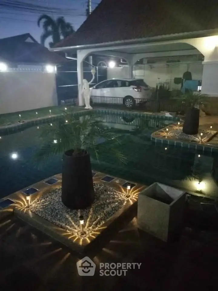 Luxurious outdoor pool area with ambient lighting and elegant landscaping, perfect for evening relaxation.