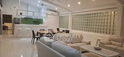 Spacious modern living room with open kitchen and elegant dining area, featuring stylish furniture and bright lighting.