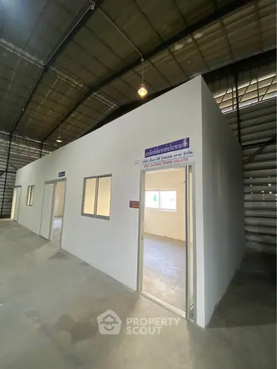 Spacious industrial warehouse interior with office partitions and high ceilings.