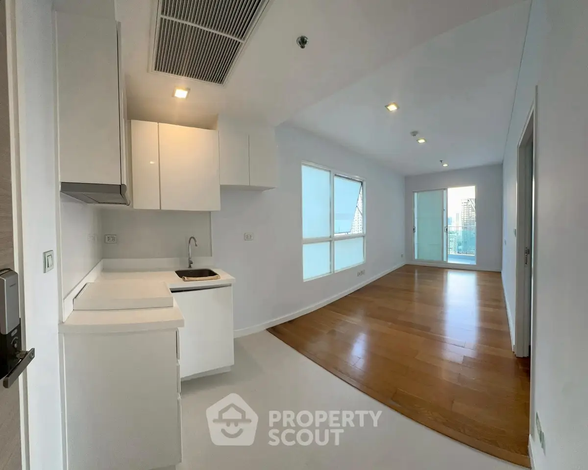 Modern open-plan kitchen and living area with wooden flooring and ample natural light.