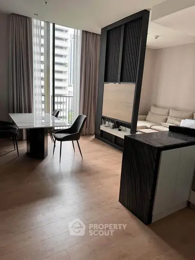 Modern living room with elegant dining area and large windows in a stylish apartment.