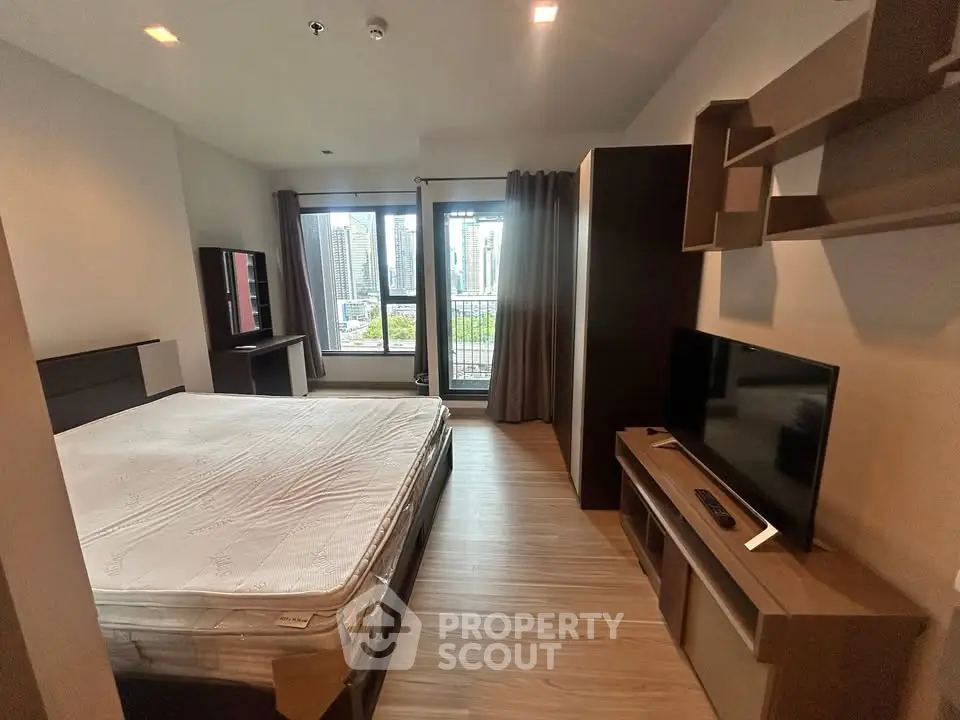 Modern bedroom with city view, featuring a large bed, TV, and stylish furniture.