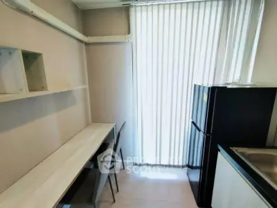 Modern kitchen with sleek design and natural light, featuring a compact dining area and refrigerator.