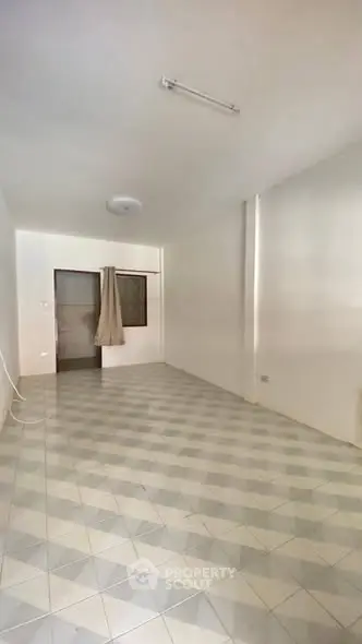 Spacious empty room with tiled flooring and neutral walls, ideal for customization.