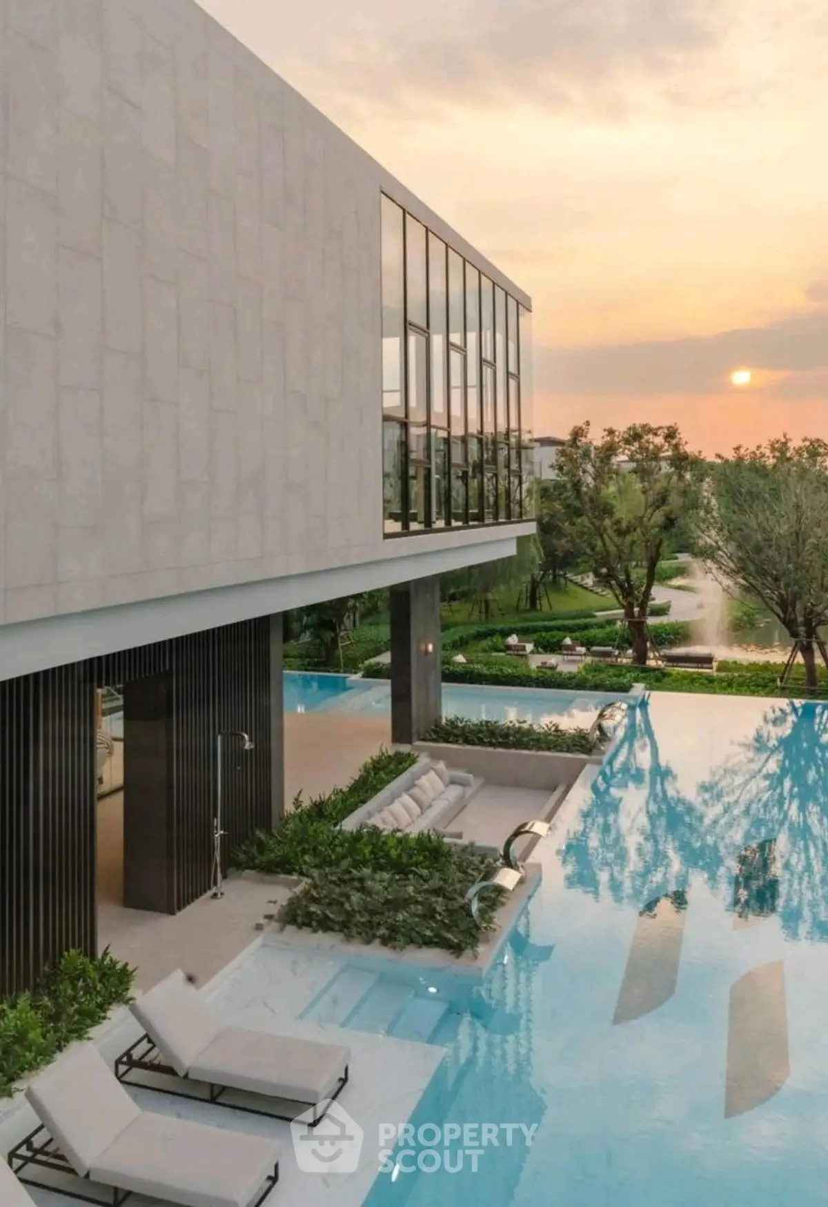 Luxurious modern villa with infinity pool and stunning sunset view, surrounded by lush greenery.