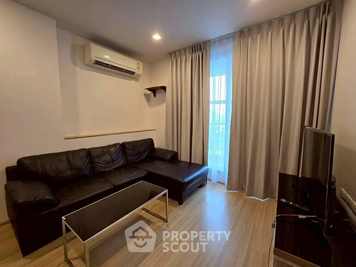 Modern living room with sleek black leather sofa and air conditioning, perfect for relaxation.