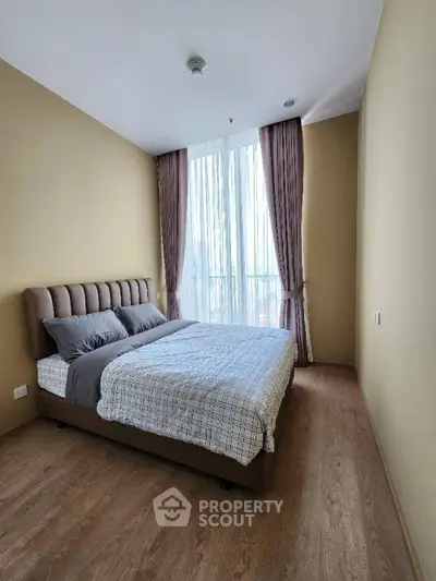 Cozy bedroom with large window and elegant curtains in modern apartment