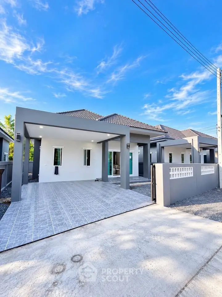 Modern single-story house with spacious driveway and sleek design under a clear blue sky.