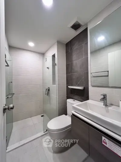 Modern bathroom with sleek design, featuring glass shower and contemporary fixtures.