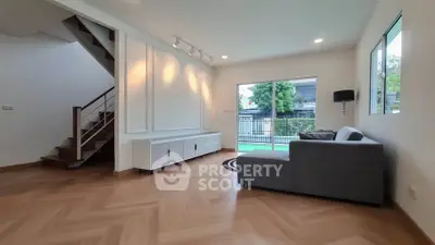 Modern living room with stylish staircase and large window overlooking garden