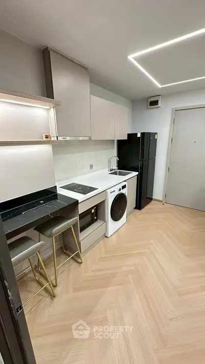 Modern kitchen with sleek cabinets, washing machine, and stylish bar stools