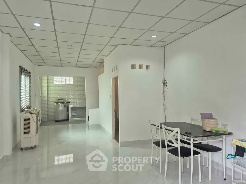 Spacious open-plan living area with dining set and modern kitchen appliances.