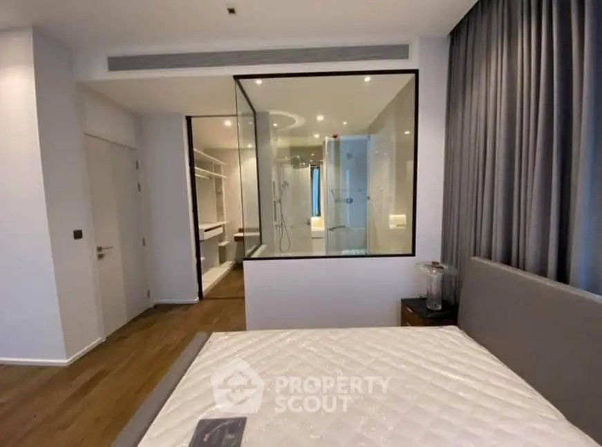 Modern bedroom with glass-walled ensuite bathroom and elegant decor