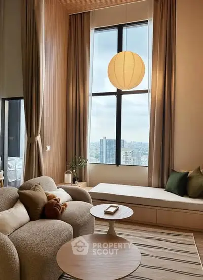 Modern living room with large window and cozy seating area in high-rise apartment.
