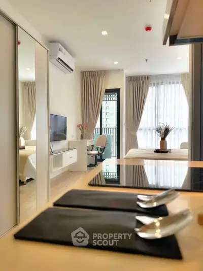 Modern open-plan apartment with sleek kitchen and cozy living area, featuring large windows and stylish decor.