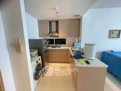 Modern kitchen with washing machine and sleek cabinetry in a compact layout.