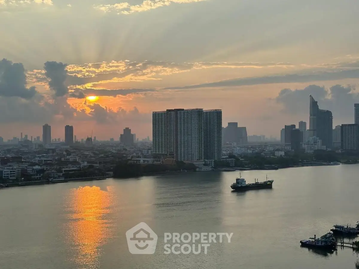 Stunning riverfront cityscape view at sunset with high-rise buildings and serene water reflections.