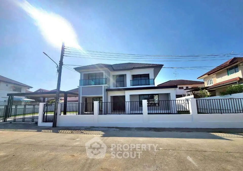 Modern two-story house with sleek design and spacious front yard under clear blue sky.