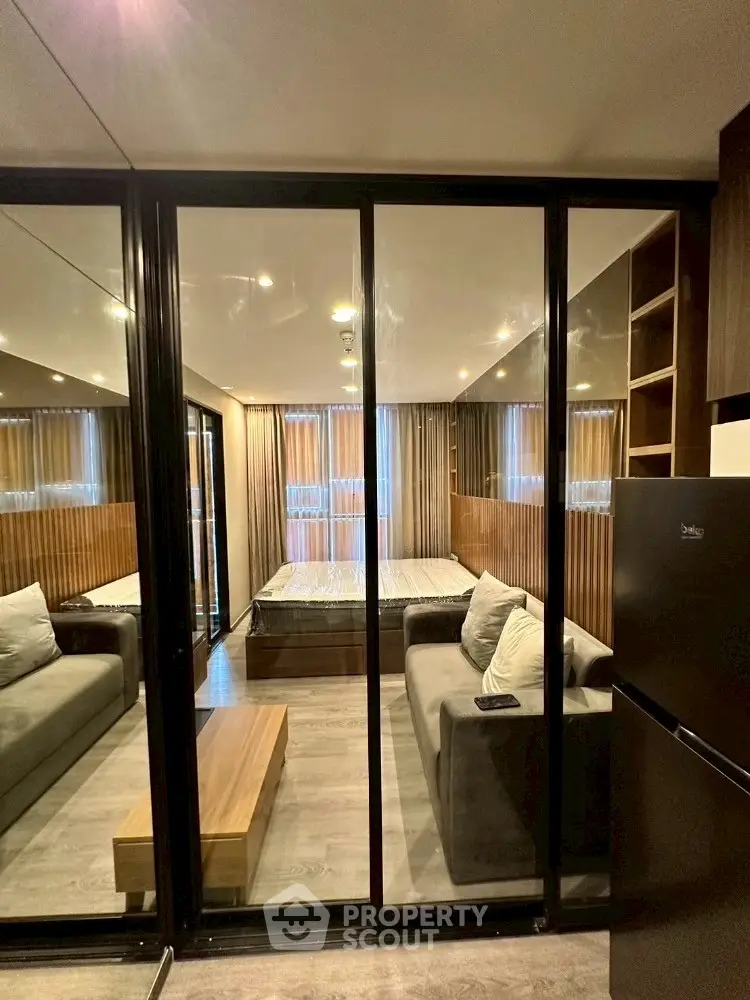 Modern studio apartment with glass partition, cozy sofa, and stylish decor.