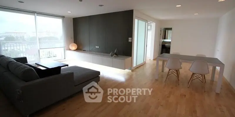 Spacious modern living room with natural light and sleek wooden flooring.
