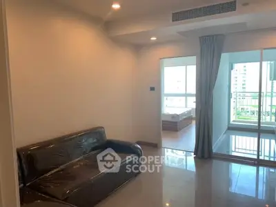 Modern apartment living room with balcony view and sleek leather sofa.