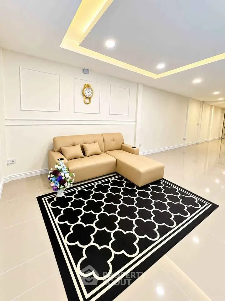 Spacious modern living room with elegant beige sofa and stylish black patterned rug.