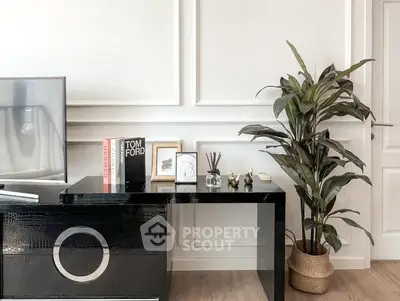 Stylish modern living room with sleek black console, decorative books, and lush indoor plant.