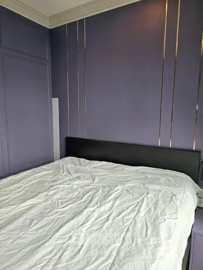 Modern bedroom with purple accent wall and stylish bed setup