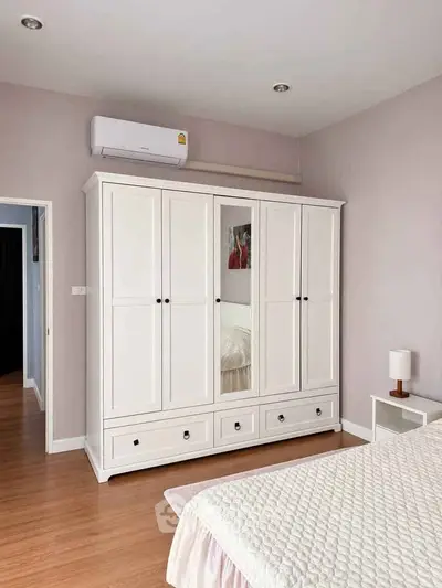 Spacious bedroom with elegant white wardrobe and cozy bed, perfect for modern living.