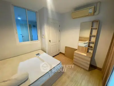 Cozy bedroom with wooden flooring and modern furniture, featuring a large mirror and air conditioning.
