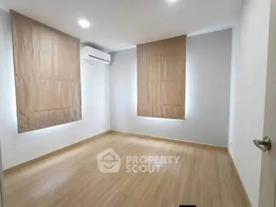 Spacious empty bedroom with wooden flooring and air conditioning