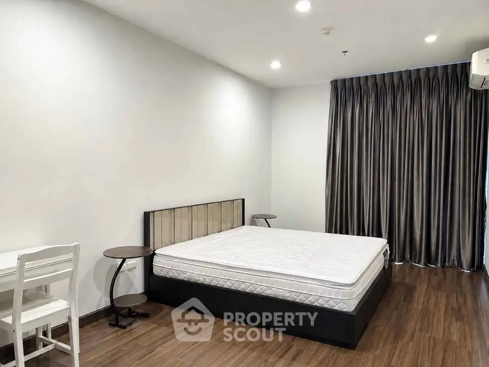 Spacious bedroom with modern furnishings and elegant curtains in a stylish apartment.