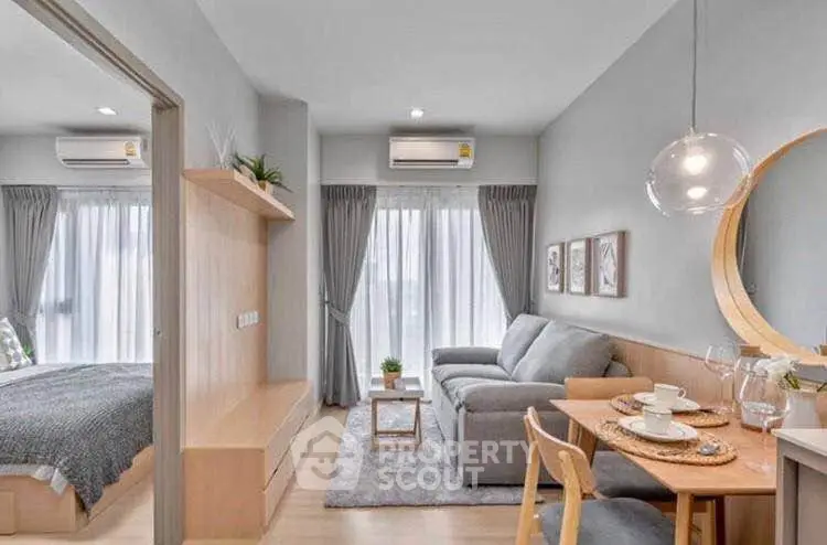 Modern living room with cozy sofa, dining area, and bedroom view in open-plan apartment.