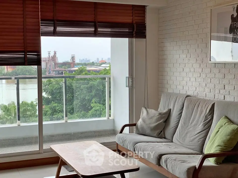 Charming living room with cozy sofa and stunning balcony view of lush greenery and cityscape.