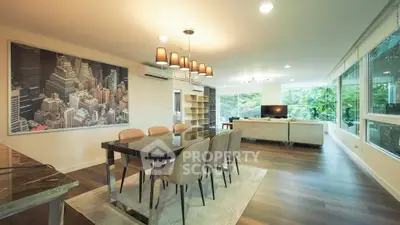 Spacious modern living room with elegant dining area and large windows offering lush garden views.