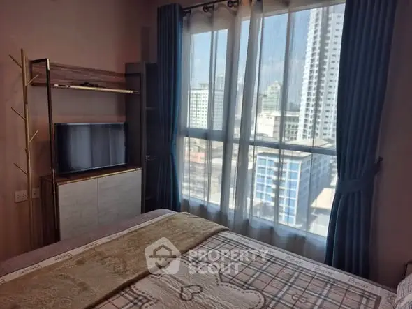 Cozy bedroom with city view and modern furnishings in high-rise apartment.