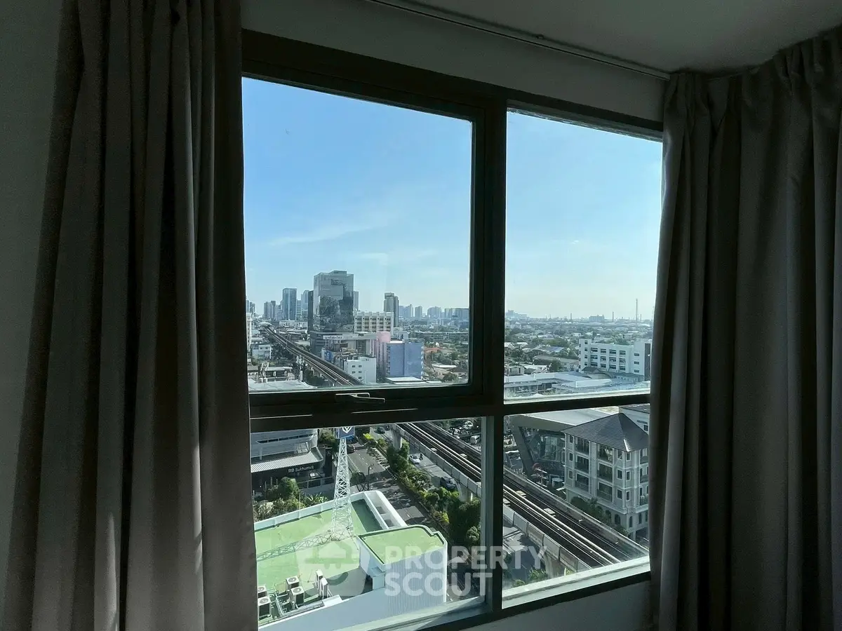 Stunning cityscape view from a high-rise apartment window, showcasing urban skyline and clear blue sky.