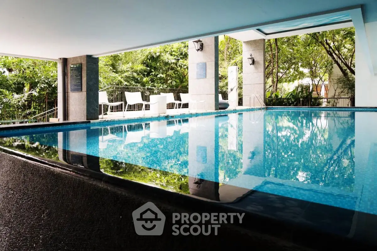 Luxurious indoor pool with seating area and lush greenery view