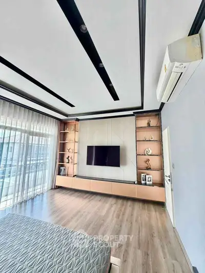 Modern bedroom with sleek design, large window, and wall-mounted TV in a luxurious apartment.