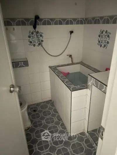 Compact bathroom with tiled walls and built-in bathtub, featuring a simple design.