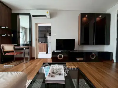 Modern living room with sleek furniture and wooden flooring, featuring a TV unit and air conditioning.