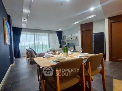 Spacious modern living room with dining area, elegant decor, and large windows offering natural light.