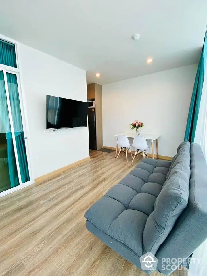 Modern living room with sleek TV, cozy sofa, and elegant dining area, featuring stylish wood flooring and bright decor.