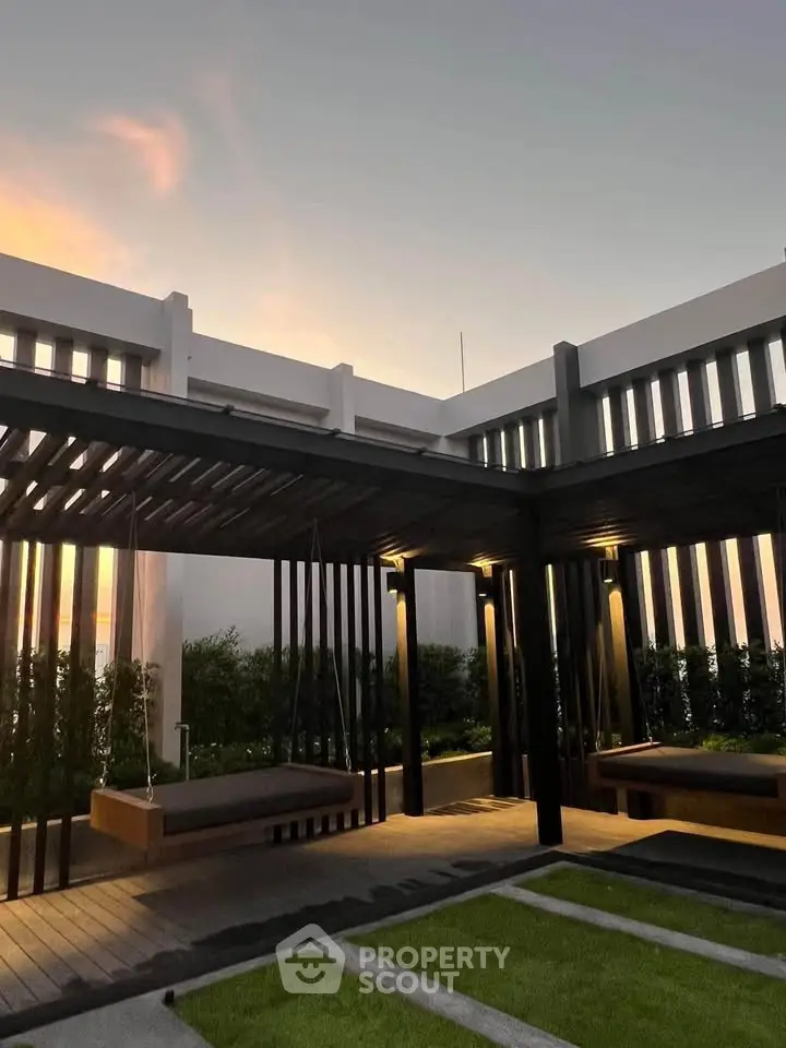 Modern outdoor seating area with pergola and lush greenery at sunset.