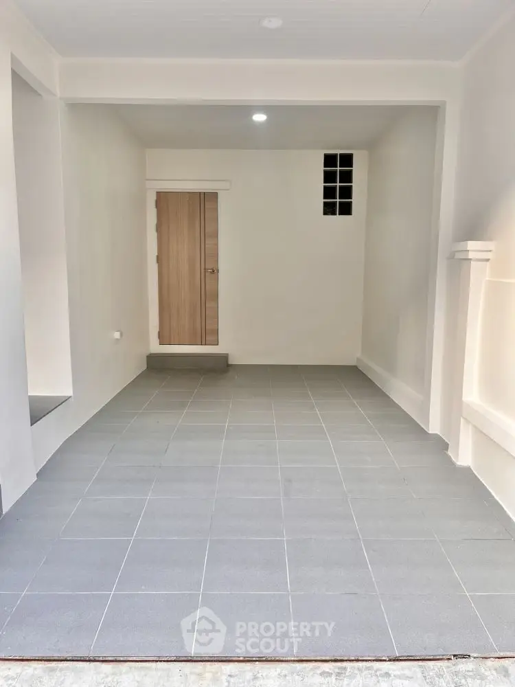 Spacious garage with modern tiled flooring and wooden door entryway.